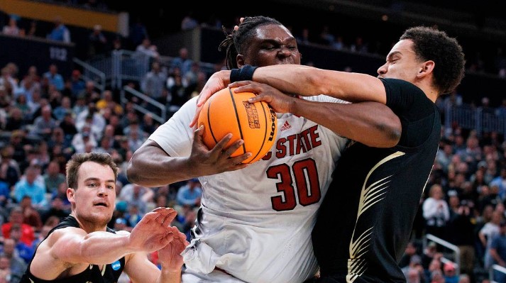 N.C. State’s DJ Burns Jr. drives to the basket against Oakland’s Jack Gohlke and Chris Conway during the second half of the Wolfpack’s 79-73 overtime win in the second round of the NCAA Tournament